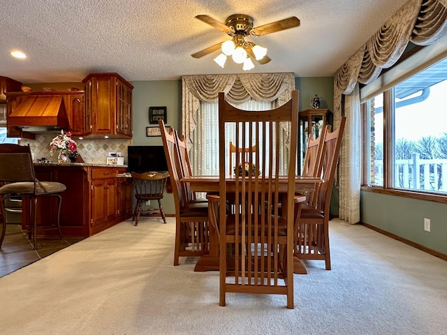 carpeted dining area featuring ceiling fan and a textured ceiling