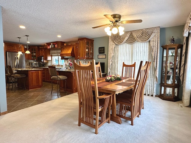 carpeted dining room with ceiling fan and a textured ceiling