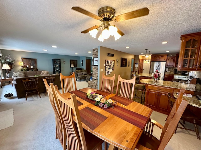 dining area featuring light carpet, a textured ceiling, and ceiling fan