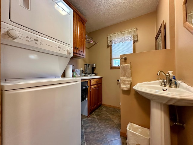 clothes washing area featuring a textured ceiling and stacked washer / dryer