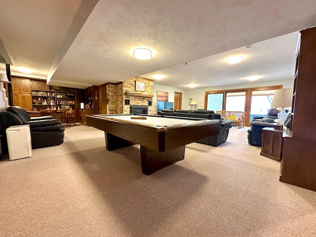 rec room with a stone fireplace, a textured ceiling, billiards, and light carpet