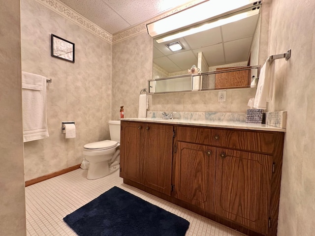 bathroom featuring a drop ceiling, vanity, and toilet