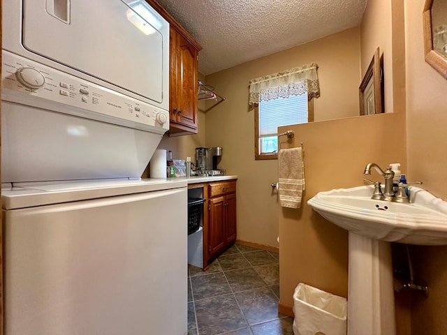1606 Shore Dr, Worthington, MN 56187 - kitchen with estacked washer and dryer, brown cabinets, a textured ceiling, light countertops, and baseboards