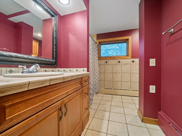 full bath with a textured ceiling, a baseboard radiator, tile patterned flooring, vanity, and tile walls