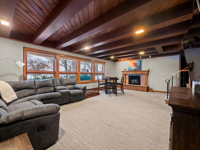 living room with carpet flooring, a glass covered fireplace, beam ceiling, and a healthy amount of sunlight