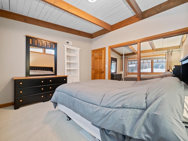 carpeted bedroom with beam ceiling, a closet, and wooden ceiling