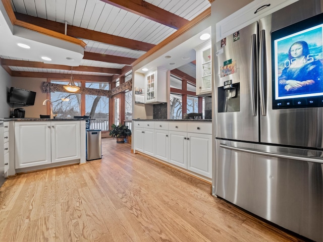 kitchen with beamed ceiling, white cabinetry, stainless steel fridge, and light hardwood / wood-style flooring