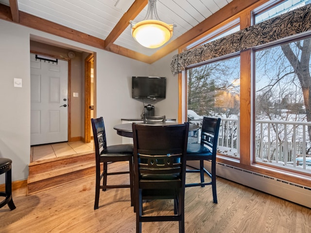 dining area featuring lofted ceiling with beams, a baseboard radiator, and light wood-type flooring