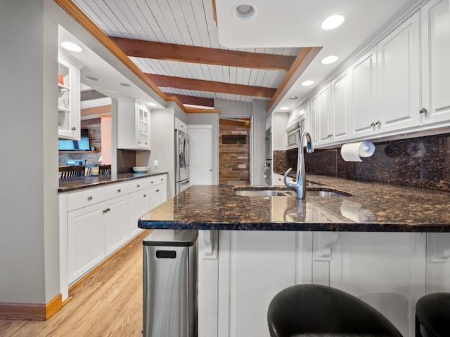 kitchen with sink, white cabinetry, beam ceiling, tasteful backsplash, and kitchen peninsula