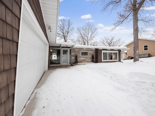 snow covered property entrance featuring a garage