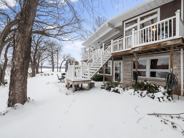 snow covered property with stairs and a wooden deck