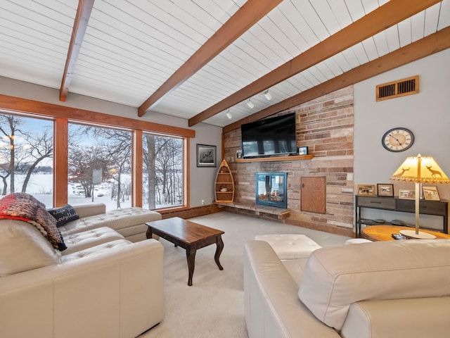 living room featuring lofted ceiling with beams, a fireplace, visible vents, and light colored carpet