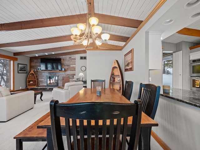 dining space with carpet floors, visible vents, a brick fireplace, a chandelier, and baseboards