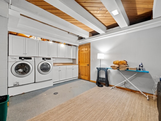 clothes washing area featuring baseboards, cabinet space, and washer and dryer