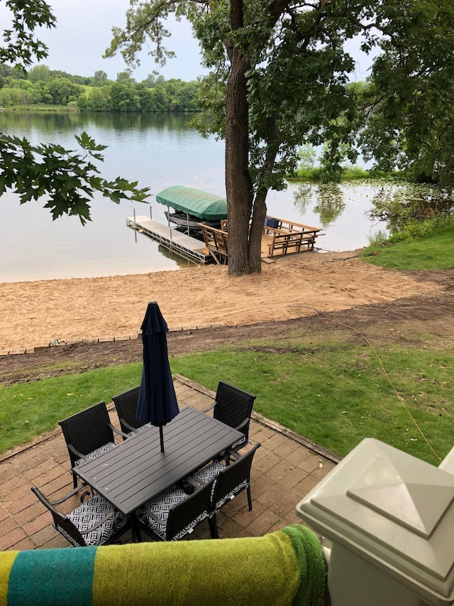 view of patio / terrace with a water view, a dock, and outdoor dining space