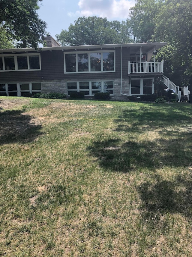 view of front of home featuring a chimney, stairway, and a front lawn