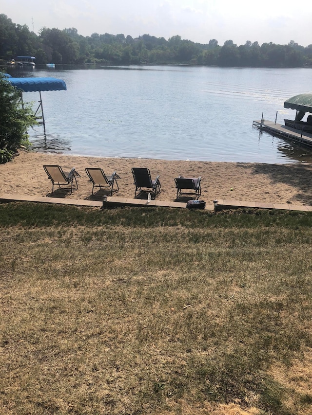 view of dock with a water view and a yard