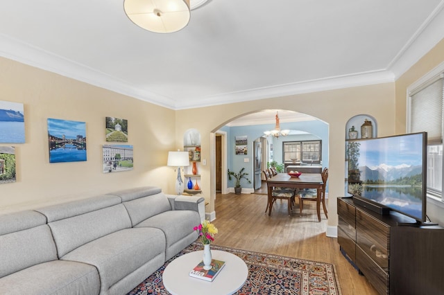 living room featuring light wood-type flooring, ornamental molding, and a chandelier