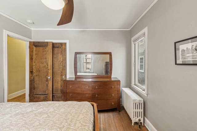 bedroom with ceiling fan, ornamental molding, light hardwood / wood-style flooring, and radiator heating unit