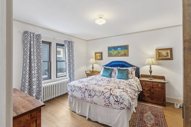 bedroom with radiator heating unit and light hardwood / wood-style floors