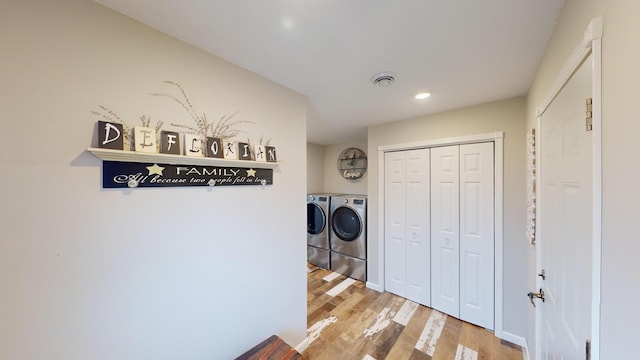 laundry room with washer and clothes dryer and light hardwood / wood-style floors