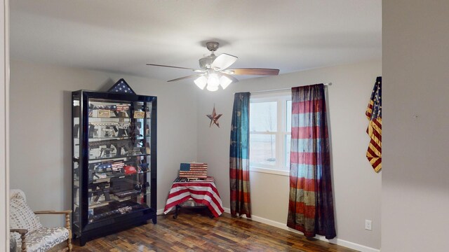 sitting room with ceiling fan and dark wood-type flooring