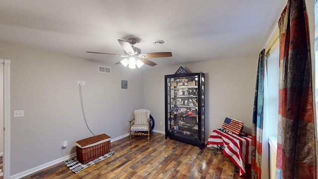 living area featuring ceiling fan and dark wood-type flooring