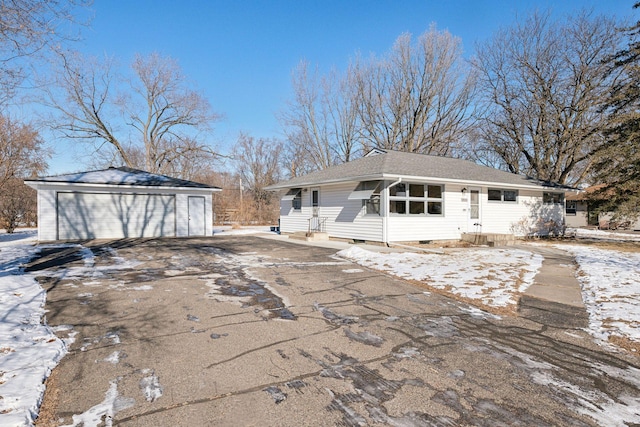 snow covered back of property with a garage and an outdoor structure