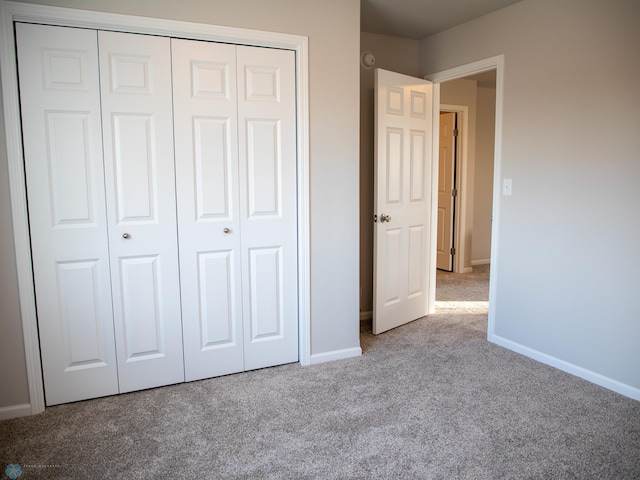 unfurnished bedroom featuring a closet and light colored carpet