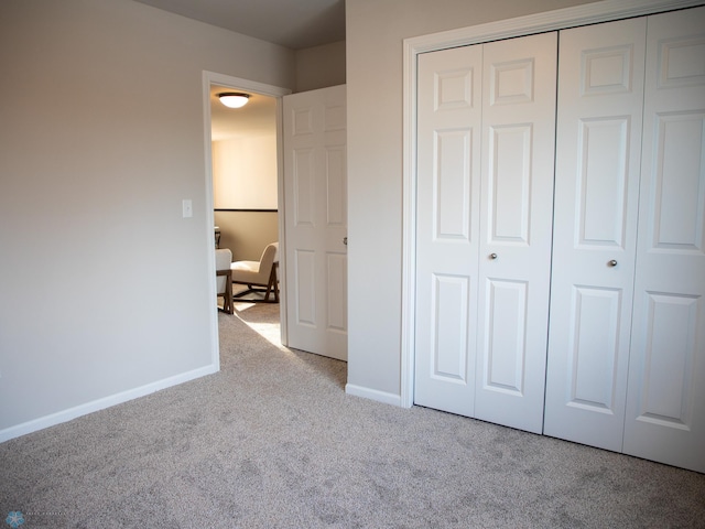 unfurnished bedroom featuring light carpet and a closet