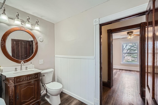 723 Lowry Ave NE, Minneapolis, MN 55418 - bathroom featuring wood finished floors, wainscoting, vanity, toilet, and a ceiling fan