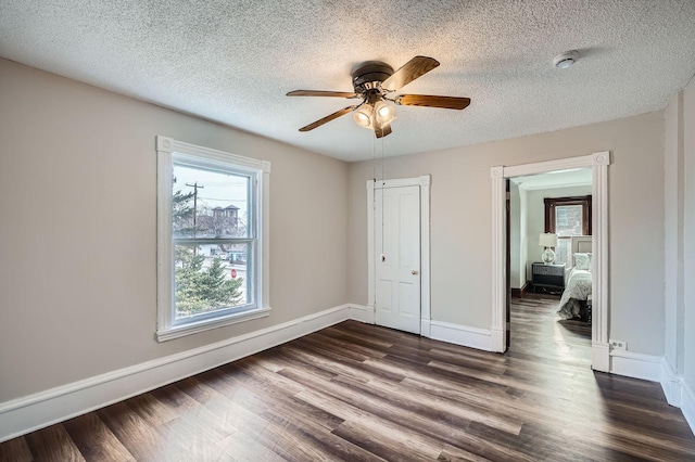 723 Lowry Ave NE, Minneapolis, MN 55418 - unfurnished bedroom with dark wood finished floors, a textured ceiling, baseboards, a ceiling fan, and a closet
