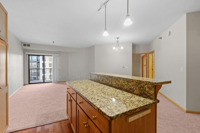 kitchen with light carpet, light stone counters, decorative light fixtures, and an inviting chandelier