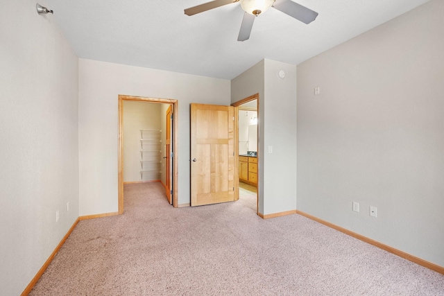 unfurnished bedroom with a walk in closet, light carpet, ceiling fan, and a closet