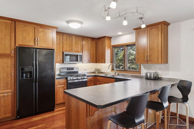 kitchen with sink, a breakfast bar area, stainless steel appliances, dark hardwood / wood-style floors, and kitchen peninsula