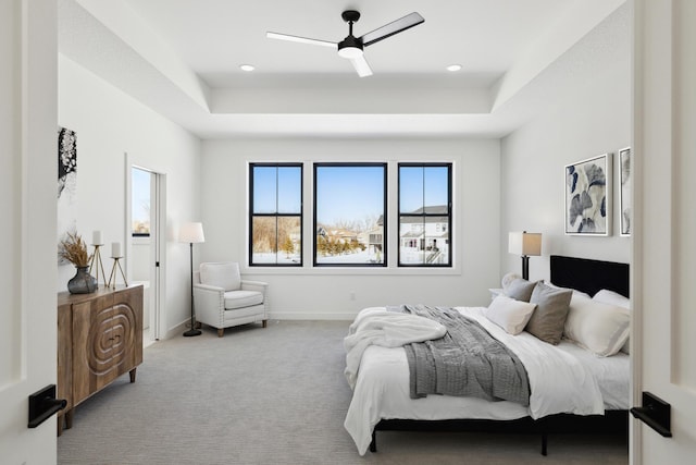 bedroom with a raised ceiling, ceiling fan, and light carpet