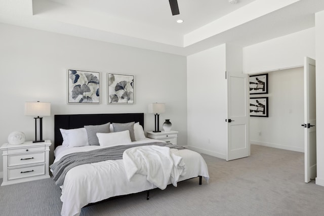 bedroom featuring light carpet, a raised ceiling, and ceiling fan