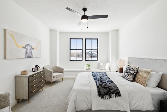 bedroom featuring light carpet, a textured ceiling, and ceiling fan