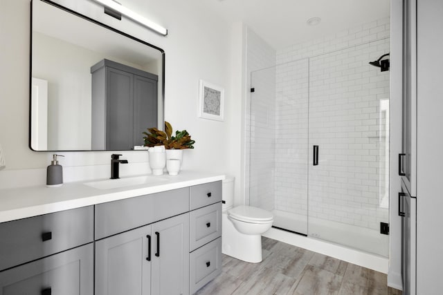 bathroom with toilet, vanity, an enclosed shower, and hardwood / wood-style flooring