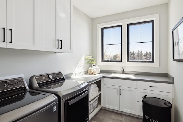 clothes washing area with washing machine and dryer, sink, and cabinets