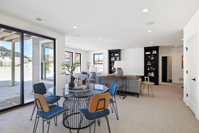 carpeted dining space with plenty of natural light and a textured ceiling