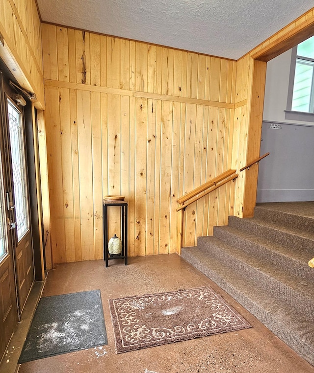 interior space with a textured ceiling and wood walls