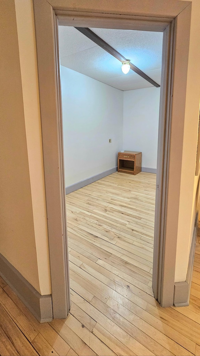 hallway with a textured ceiling and light hardwood / wood-style floors