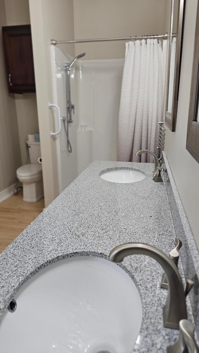 bathroom featuring hardwood / wood-style flooring, curtained shower, toilet, and vanity