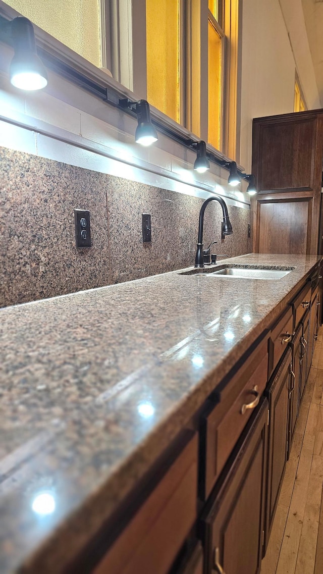 interior space featuring sink, hardwood / wood-style floors, dark stone counters, and tasteful backsplash