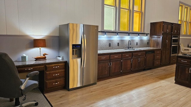 kitchen featuring sink, appliances with stainless steel finishes, light hardwood / wood-style flooring, and dark stone countertops