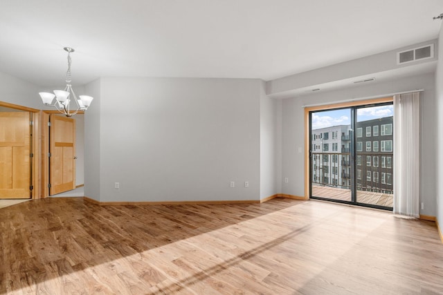 spare room featuring an inviting chandelier and light hardwood / wood-style floors