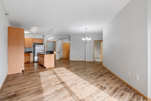 kitchen featuring a center island, light hardwood / wood-style flooring, stainless steel fridge, and decorative light fixtures