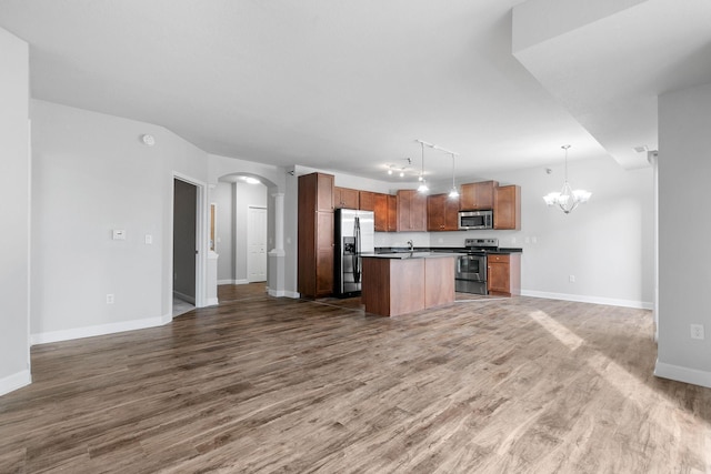 kitchen with a kitchen island, a chandelier, hanging light fixtures, stainless steel appliances, and dark wood-type flooring