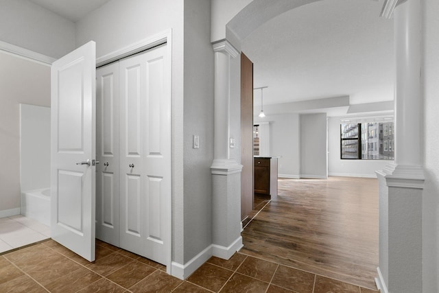 hallway with dark tile patterned flooring and decorative columns